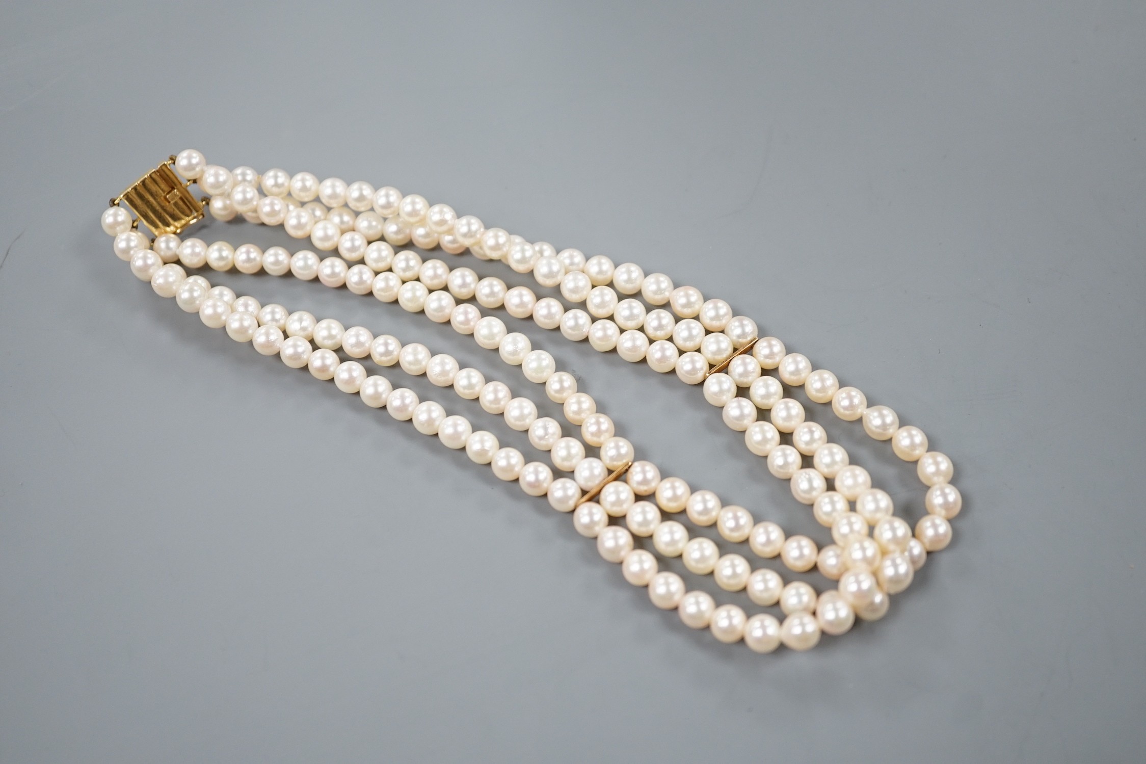 A triple strand cultured pearl necklace with 750 yellow metal clasp, 32cm.